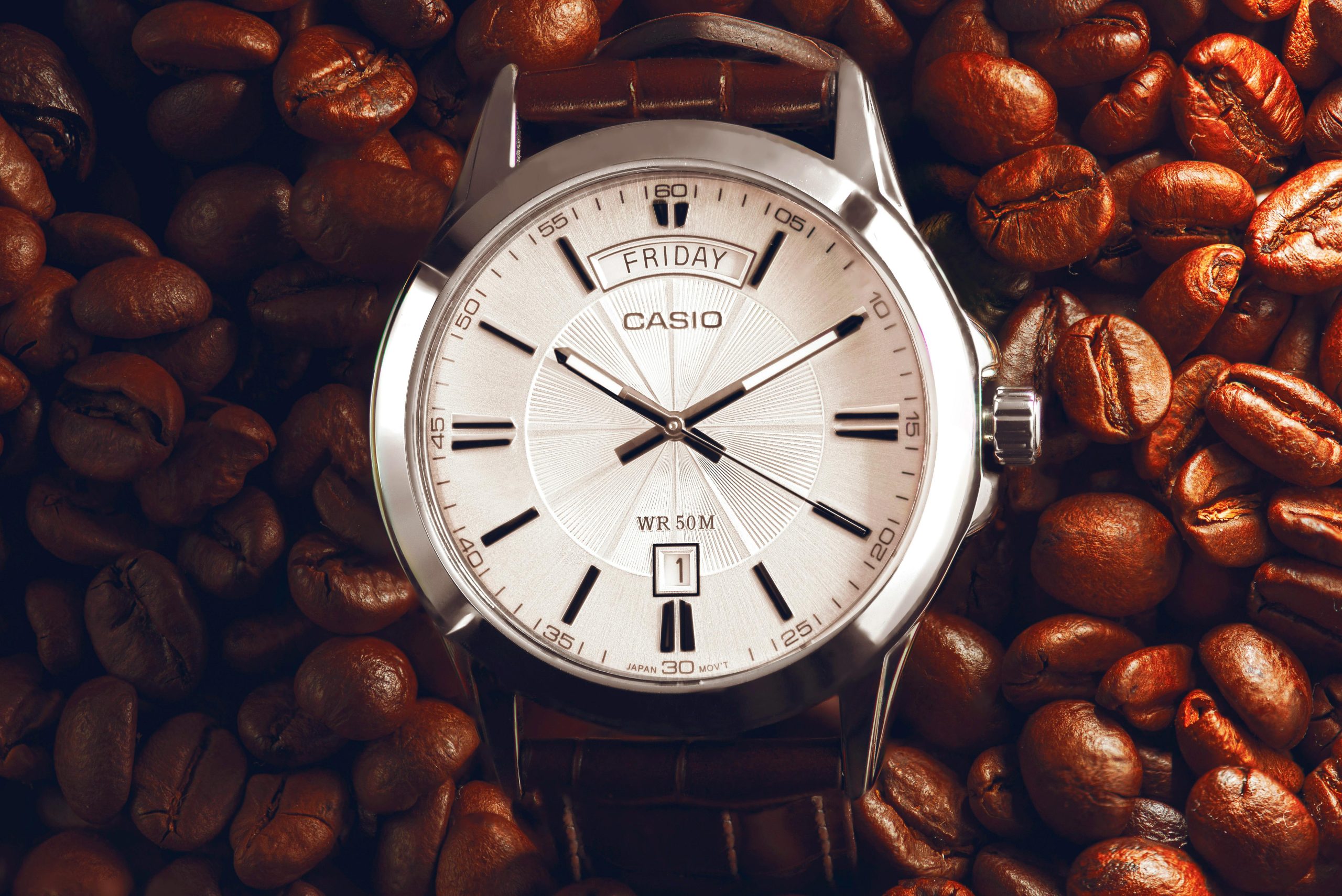 Casio analog wristwatch elegantly placed on roasted coffee beans for a modern and conceptual look.